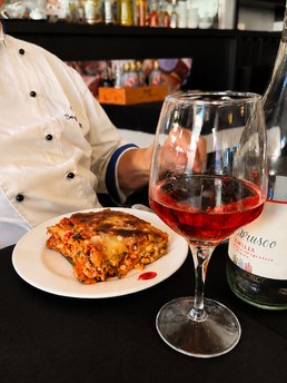Fatia de lasanha com um copo de vinho tinto